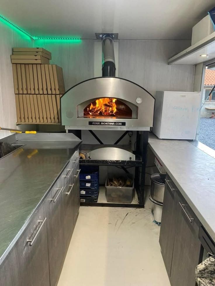 Custom food truck pizza oven installation inside a commercial mobile kitchen built by professional food truck builders.